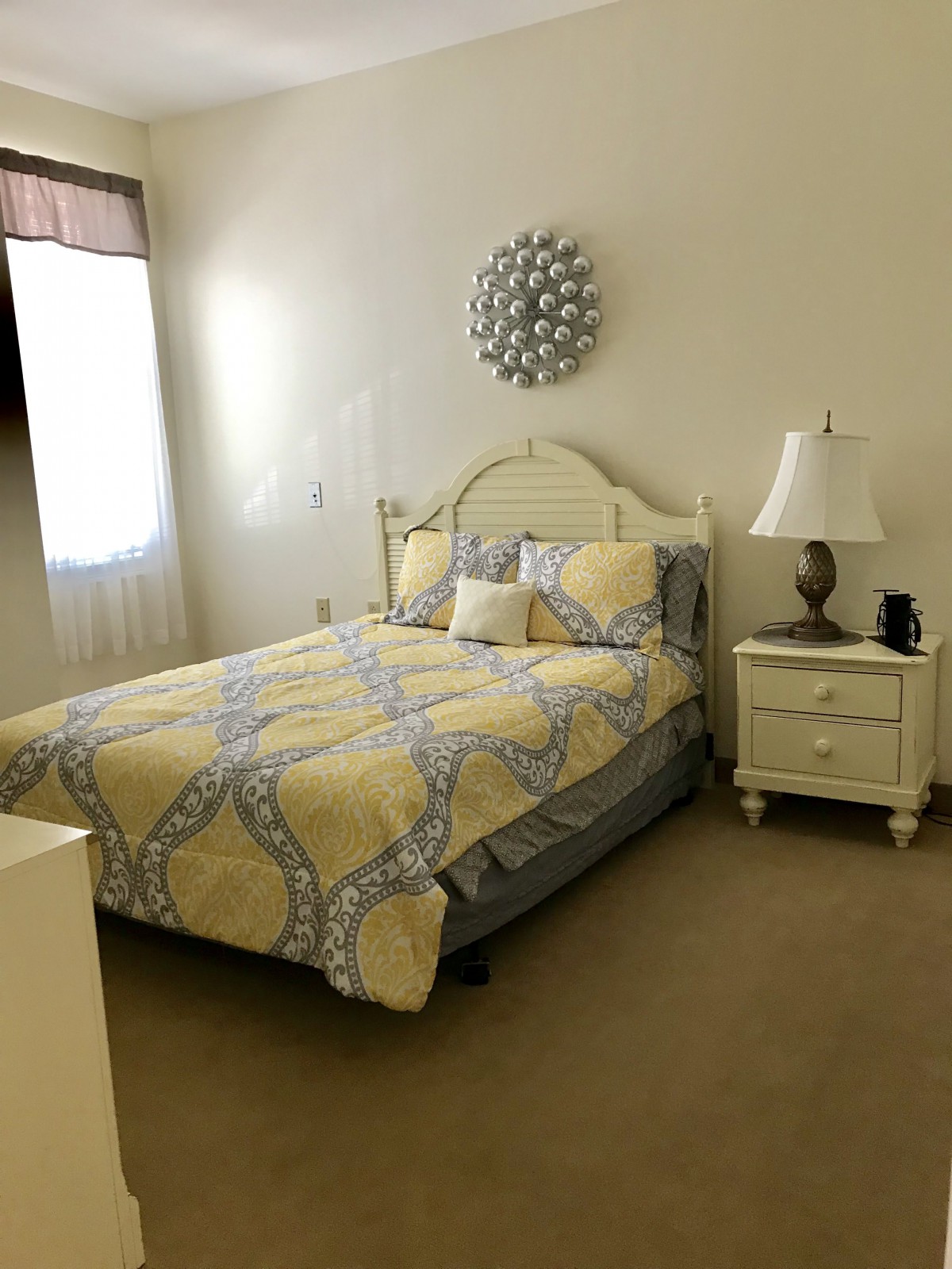 A cozy and well-decorated bedroom with a neatly made bed and a bedside table.