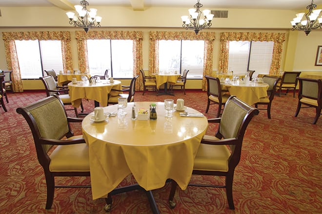 A cozy dining room with elegantly set tables and comfortable chairs.