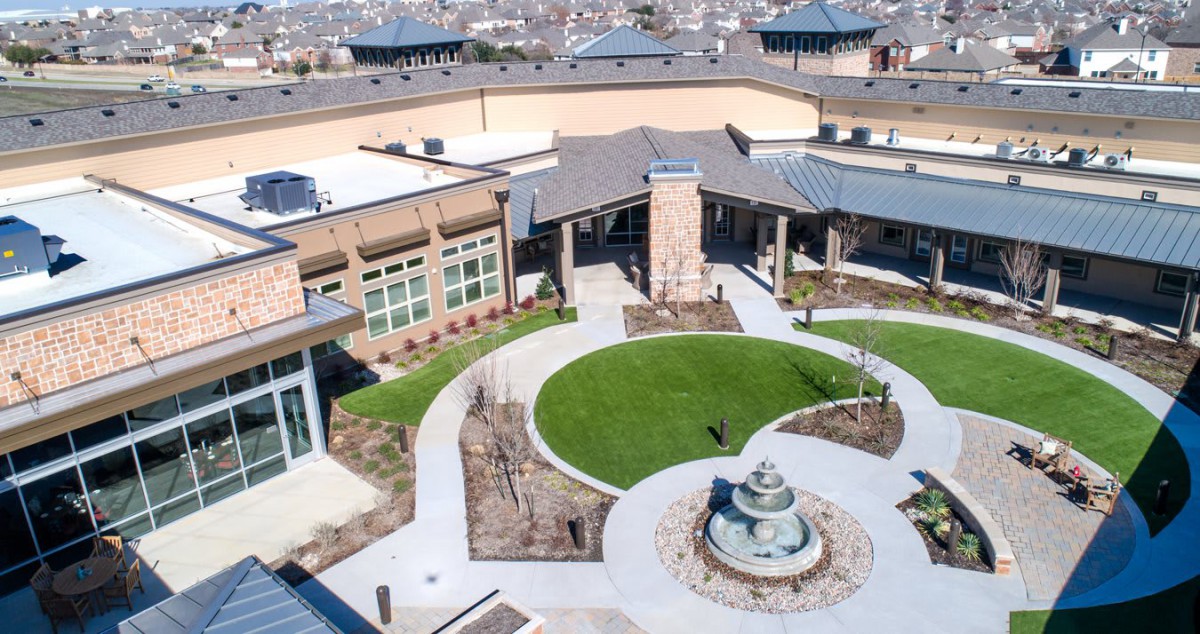 Aerial view of a modern building with a landscaped courtyard featuring a central fountain.
