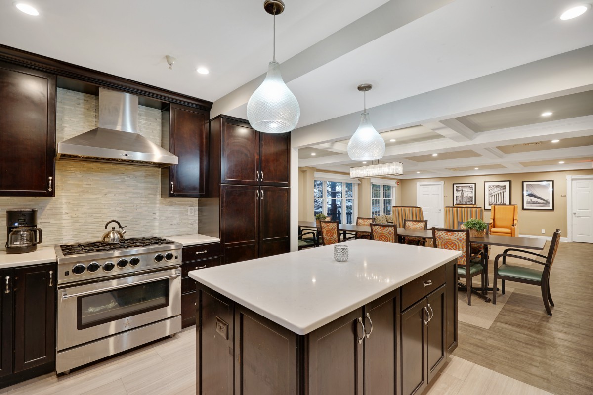 A modern kitchen with a large island, stainless steel appliances, and dark cabinetry.