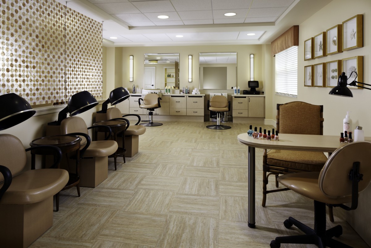 An empty salon with styling chairs, hair dryers, and a nail station.