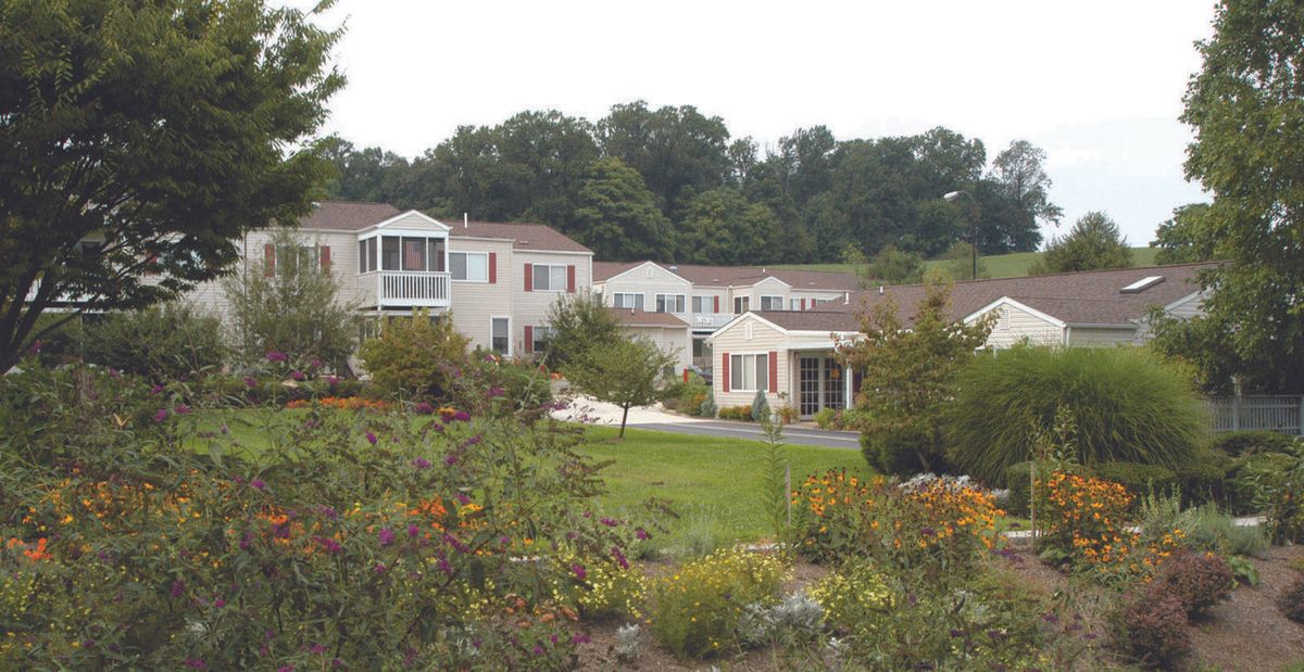 A scenic view of a suburban neighborhood surrounded by lush greenery and gardens.