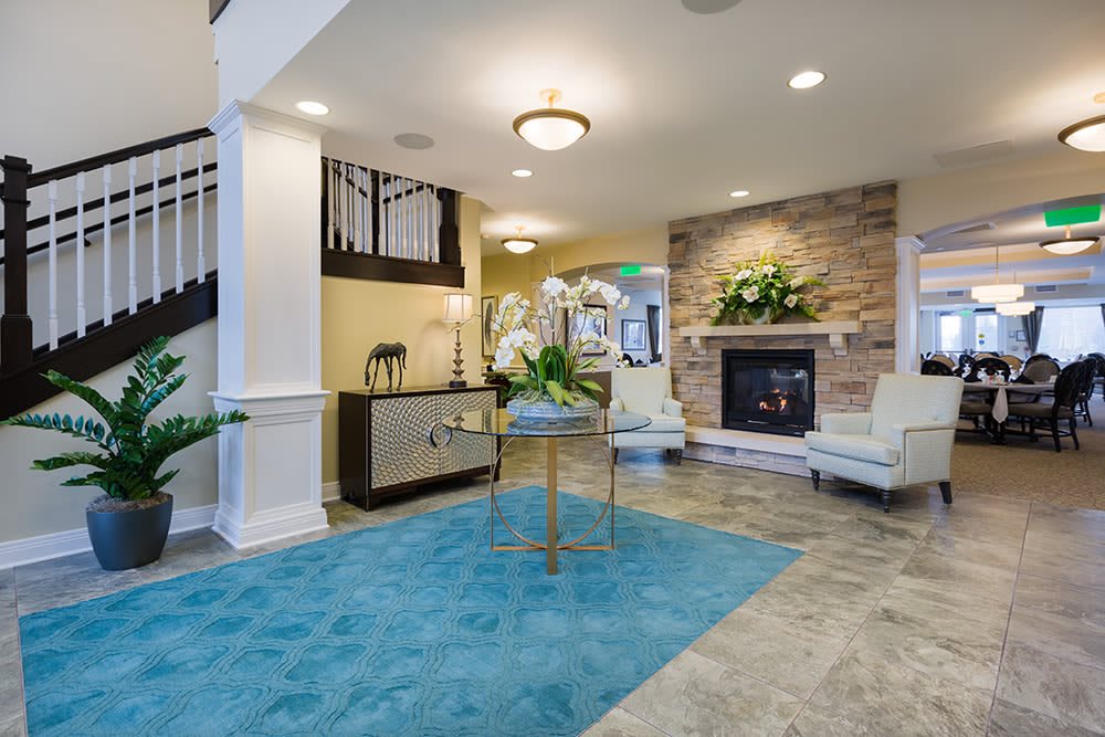 A modern living room with a cozy fireplace, elegant furniture, and a striking blue rug.