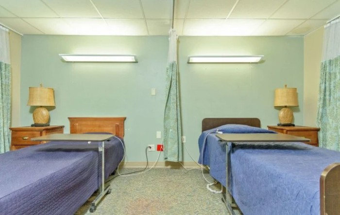 An empty hospital room with two beds separated by a curtain.