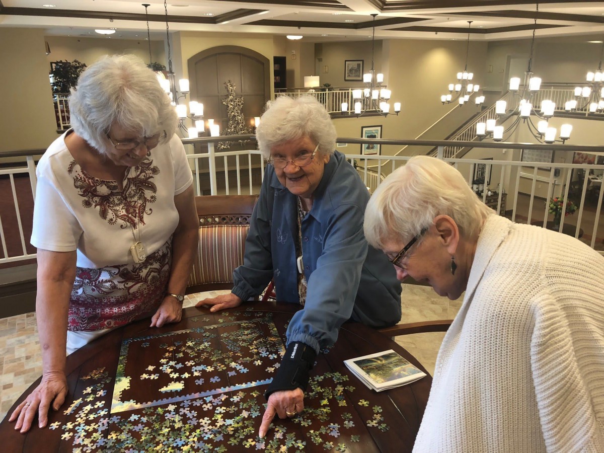 A group of seniors working on a puzzle together in a community space.