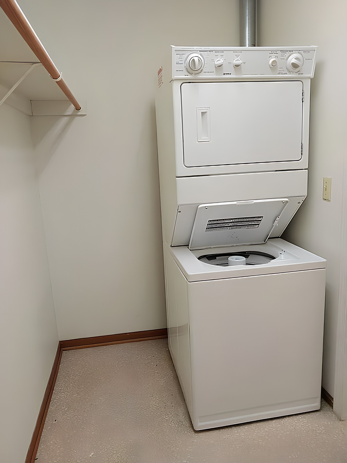 A compact laundry room featuring a stacked washer and dryer unit.
