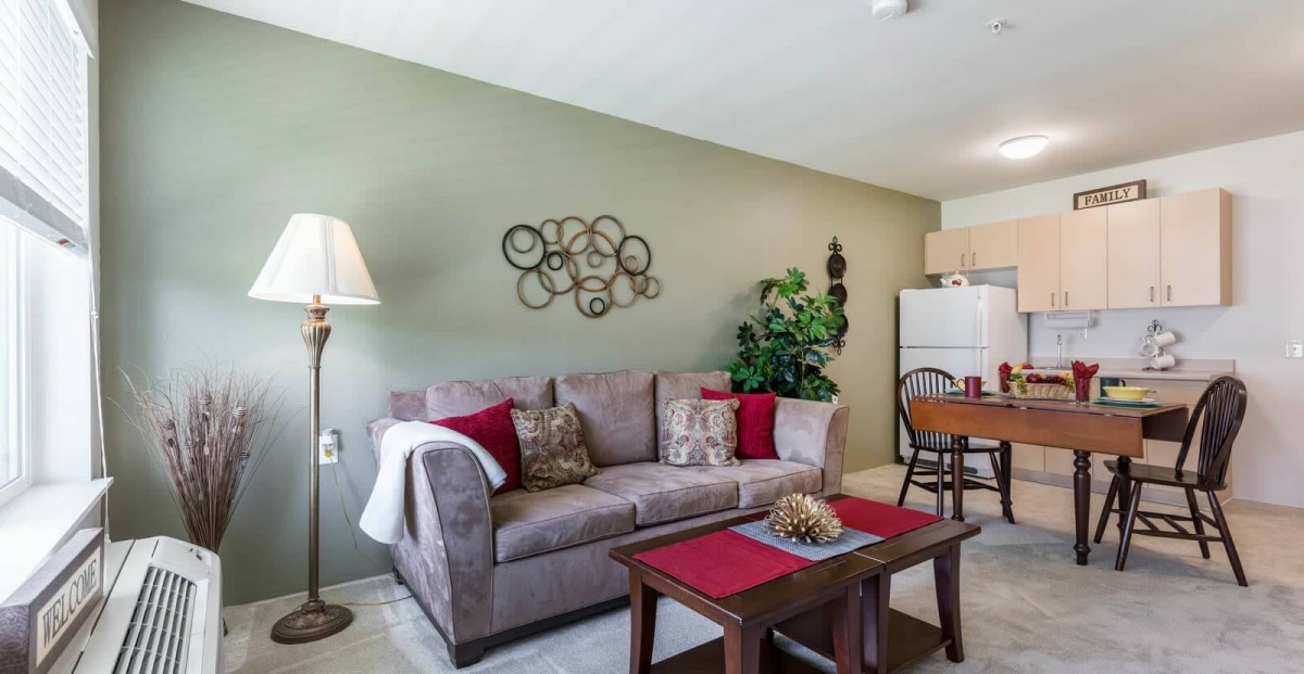 A cozy living room featuring a gray sofa with red pillows, a wooden coffee table, and decorative wall art.