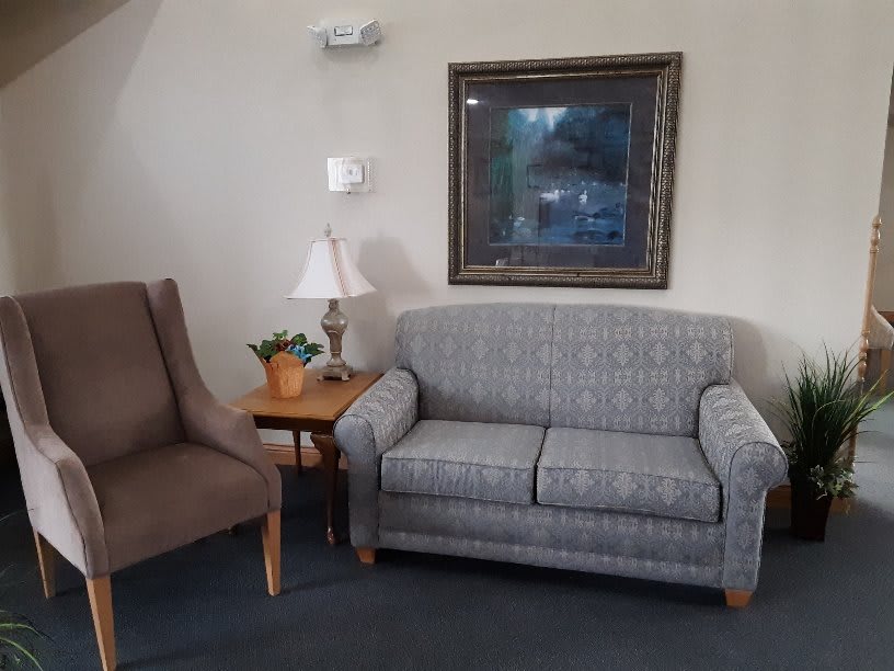 A cozy living room setup featuring a sofa, chair, table, and a lamp with wall decor.