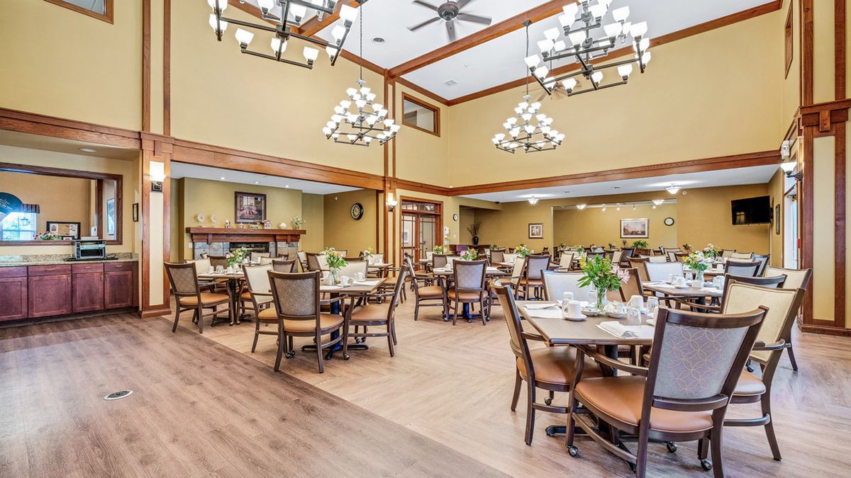 An elegant dining room featuring wooden tables, comfortable chairs, and decorative chandeliers.