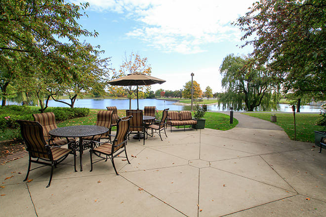 A scenic view of an outdoor seating area by the lake in a park.