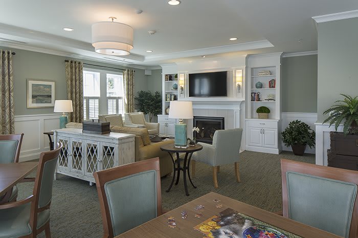 A well-designed living room featuring comfortable seating, a wall-mounted television above a fireplace, and built-in shelving for decor.