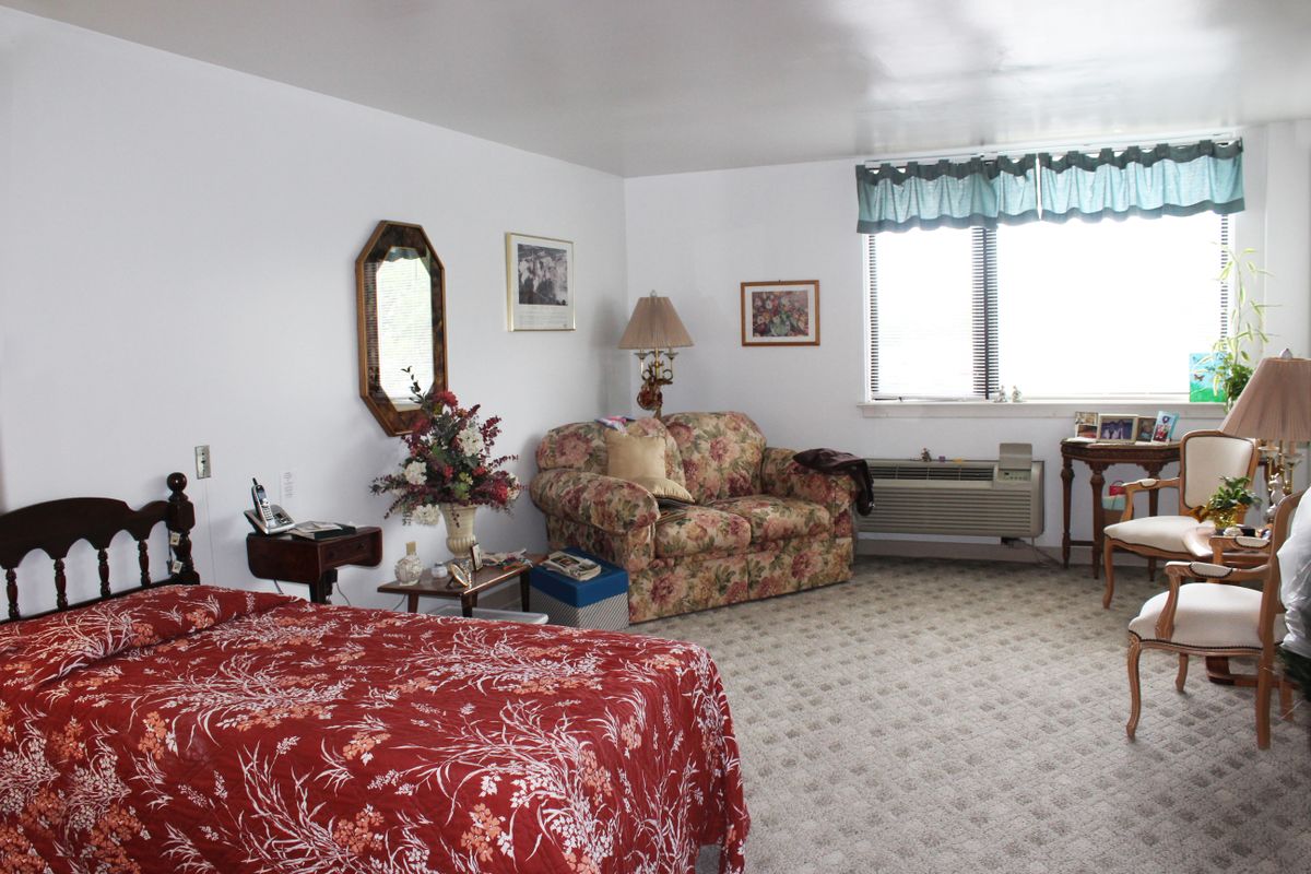 A cozy bedroom with floral-patterned furniture and a window with blue curtains.