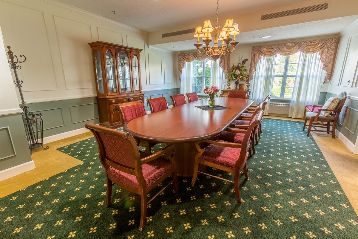 Elegant dining room with a long wooden table, upholstered chairs, and a chandelier.