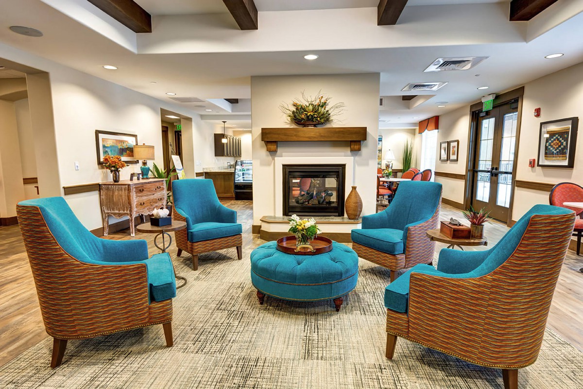 A modern living room interior with blue chairs arranged around a fireplace.