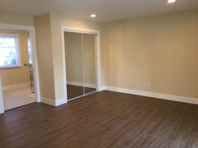 A spacious, empty room with hardwood floors and sliding closet doors.