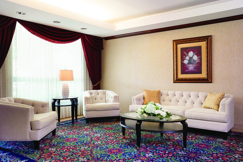 A cozy living room with elegant sofas, a vibrant carpet, and decorative artwork on the wall.