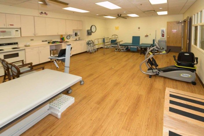 A spacious rehabilitation room equipped with various exercise machines and treatment tables.