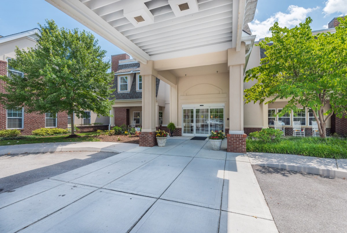 A modern building entrance with a covered walkway and surrounding trees.
