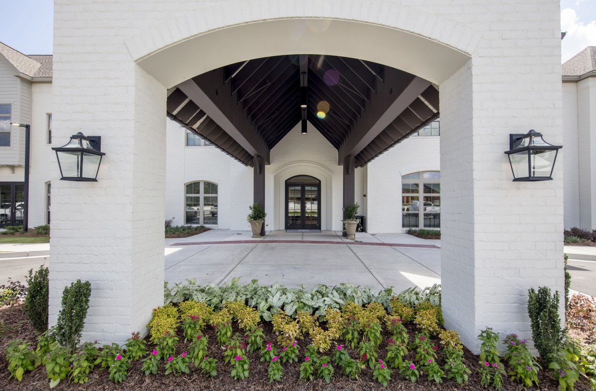 A building entrance with a covered walkway and landscaped plants.
