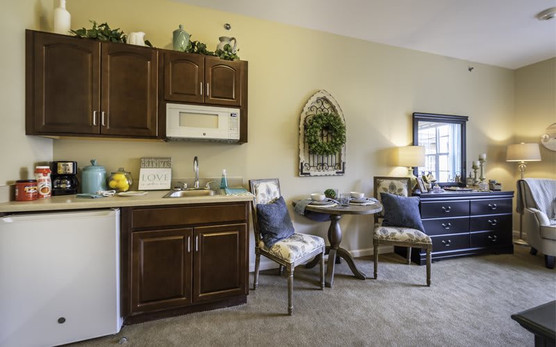 Cozy kitchen and dining area with wooden cabinets, a microwave, and a small round table with two chairs.