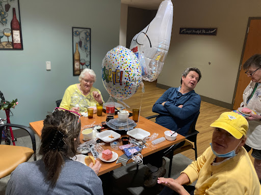 A warm gathering of friends and family celebrating with food and balloons.