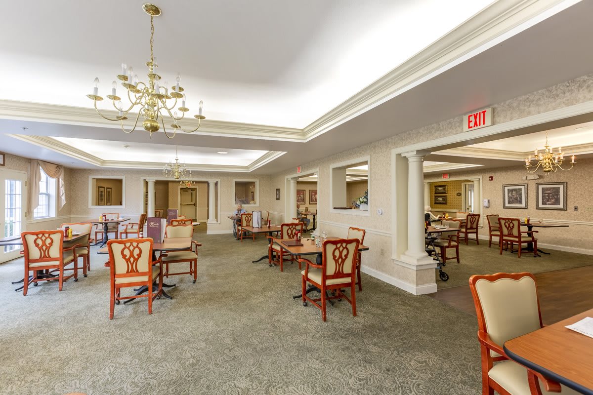 A spacious dining area with elegant chairs and tables, featuring a chandelier and detailed ceiling design.