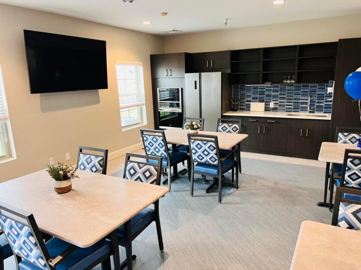 A modern kitchen and dining area with tables, chairs, and a television.