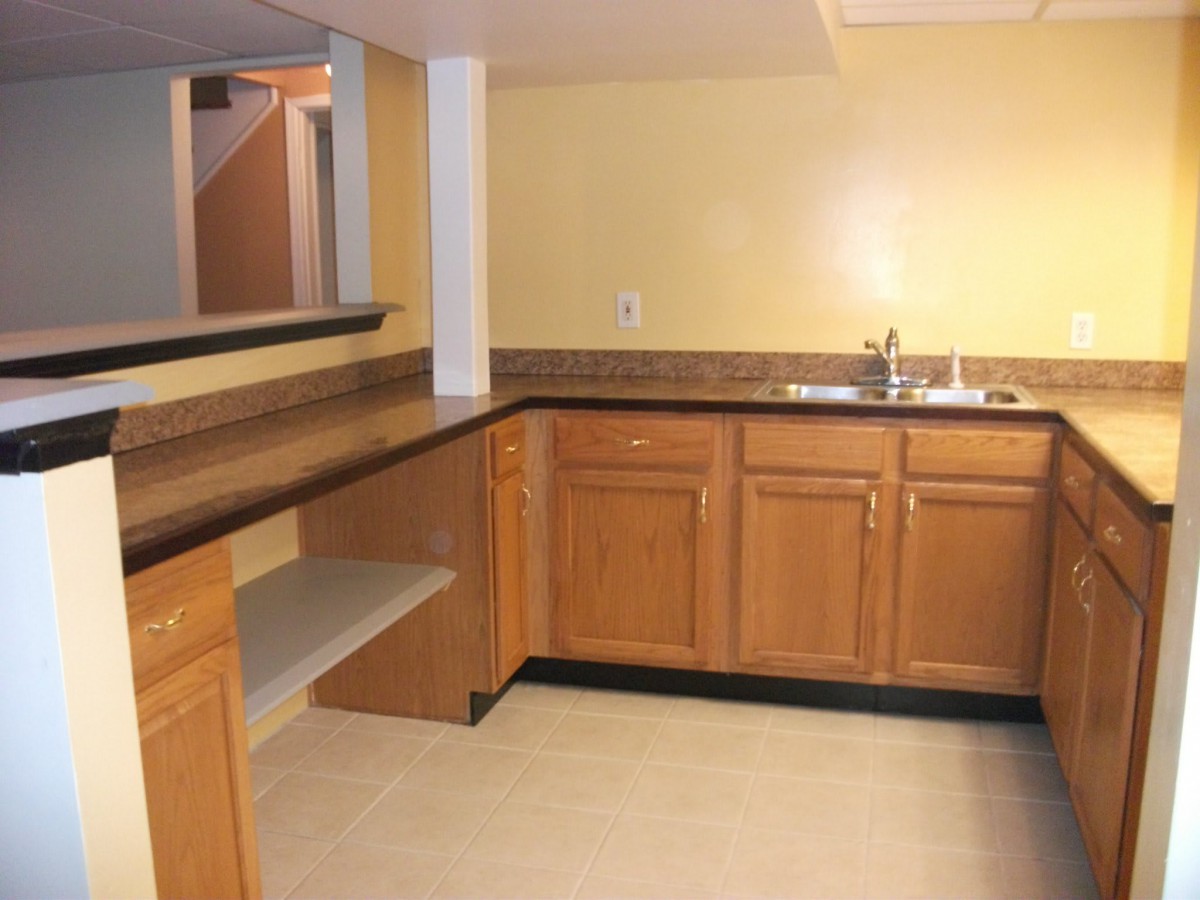 A bar area with wooden cabinets and a countertop sink.