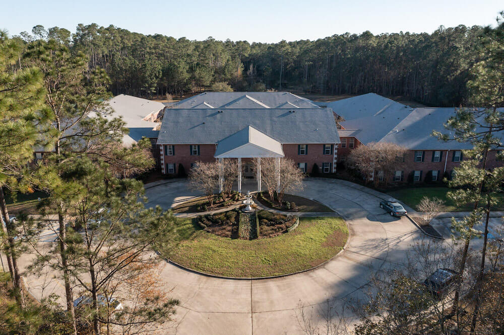 Aerial view of a large building with a circular driveway surrounded by trees.