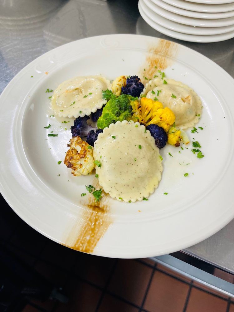 A gourmet dish featuring ravioli with vibrant roasted cauliflower and herbs, elegantly plated.