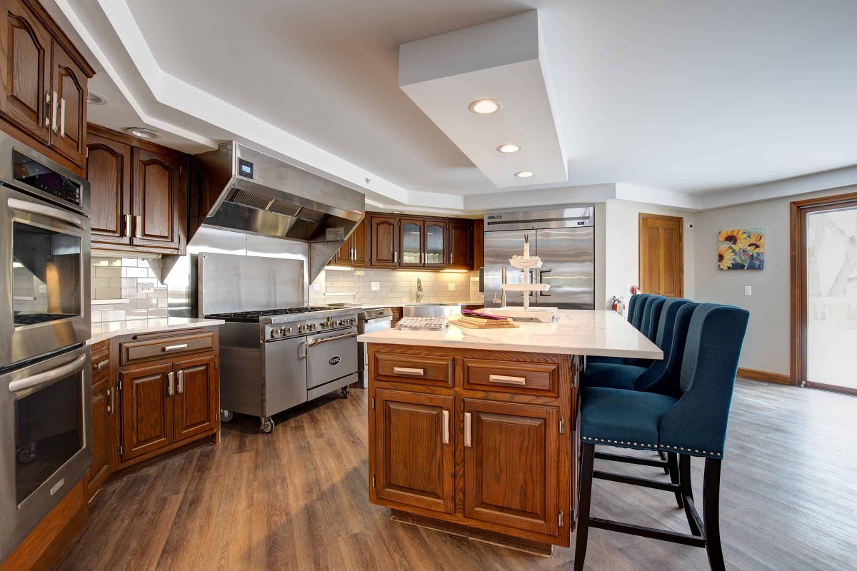 A modern kitchen with wood cabinets, a large island, and stainless steel appliances.
