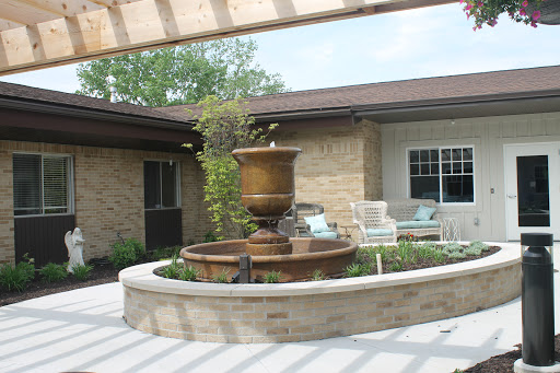 A serene outdoor space featuring a beautiful fountain surrounded by lush greenery and comfortable seating.