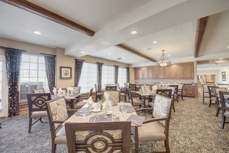 An elegant dining area with neatly arranged tables and chairs, featuring ambient lighting.