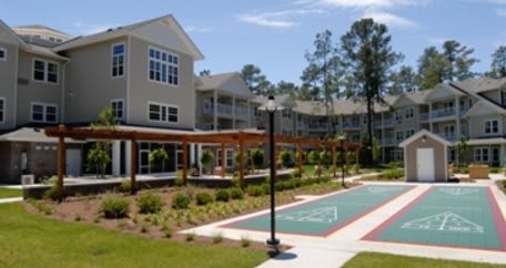 A modern apartment complex featuring a landscaped outdoor recreation area and sunny weather.