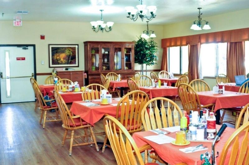 A cozy dining room with wooden tables and chairs, set for meals.