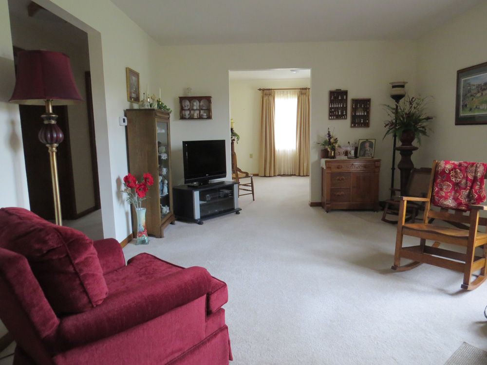 A cozy living room with a TV, red sofa, and various pieces of furniture and decorations.