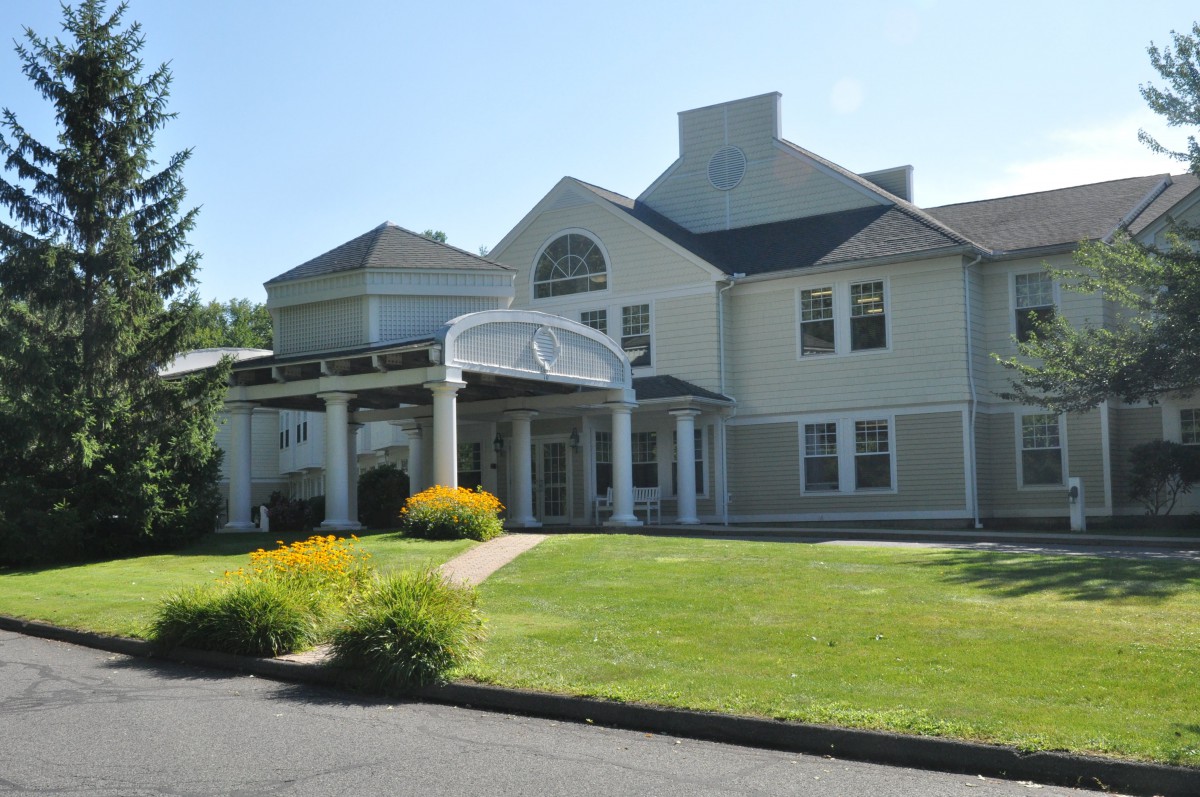 A large residential building with a well-maintained lawn and garden.