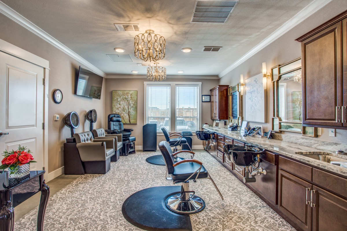 A modern salon interior featuring styling chairs, mirrors, and hair dryers with elegant lighting.