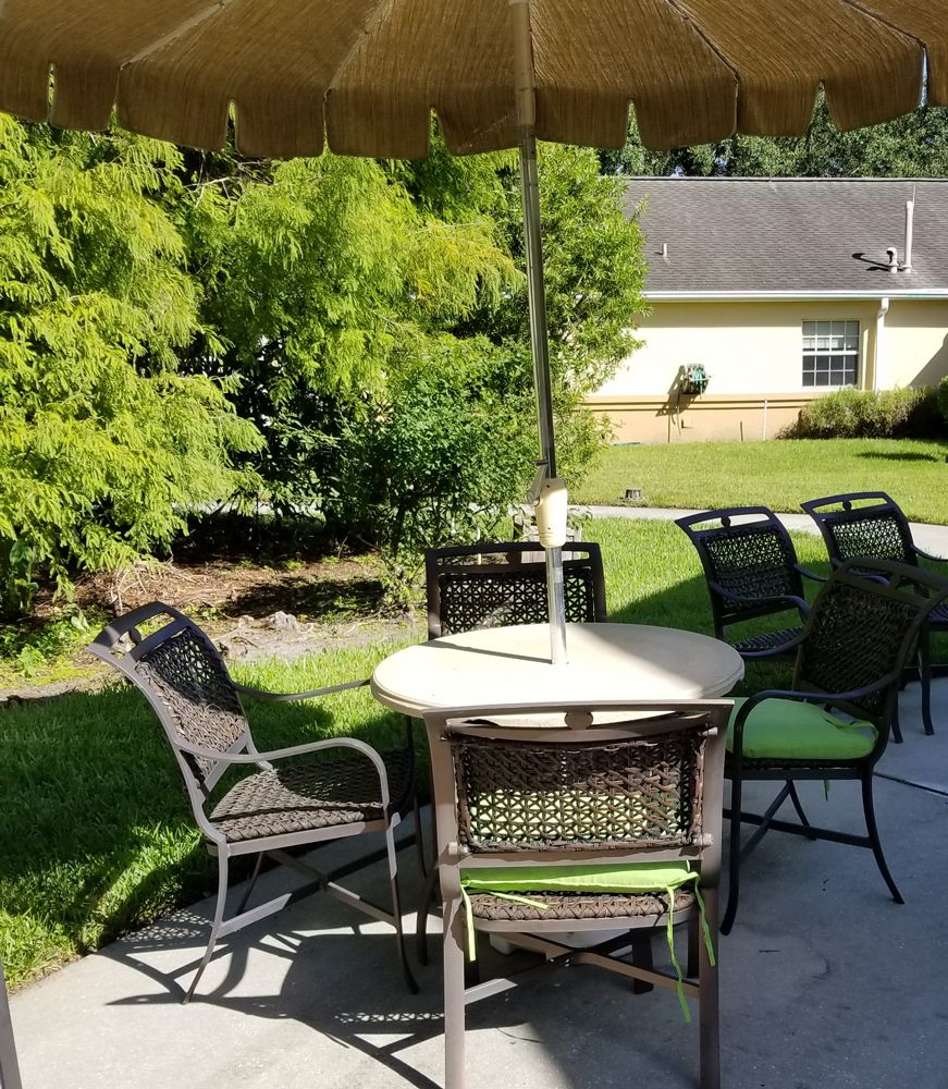 Outdoor patio area with a table, chairs, and umbrella on a sunny day.