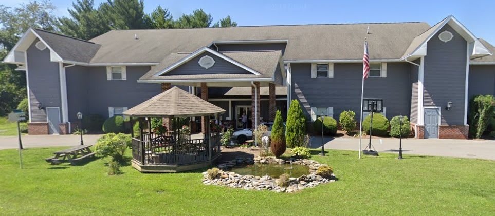 A picturesque building with a gazebo and pond surrounded by well-maintained landscaping on a sunny day.