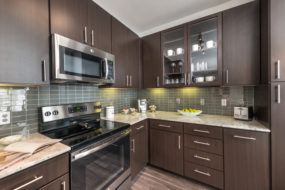 A modern kitchen with dark wood cabinets and stainless steel appliances.