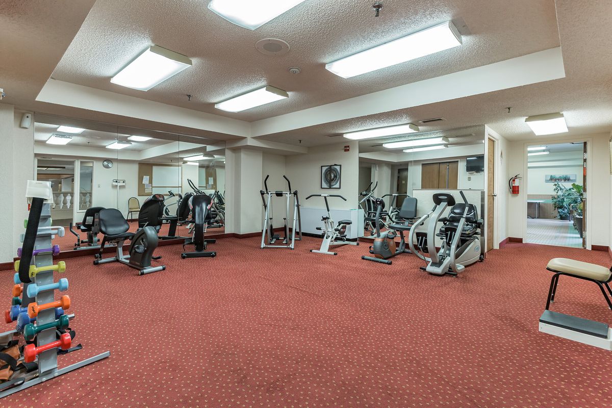 A spacious gym with various exercise equipment including treadmills and ellipticals.