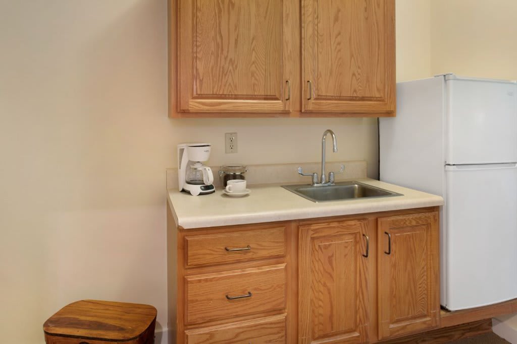 A small kitchen area with wooden cabinets, a sink, and a coffee maker on the countertop.