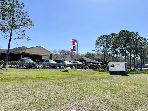 A view of a building with flags flying, surrounded by greenery and under a clear blue sky.