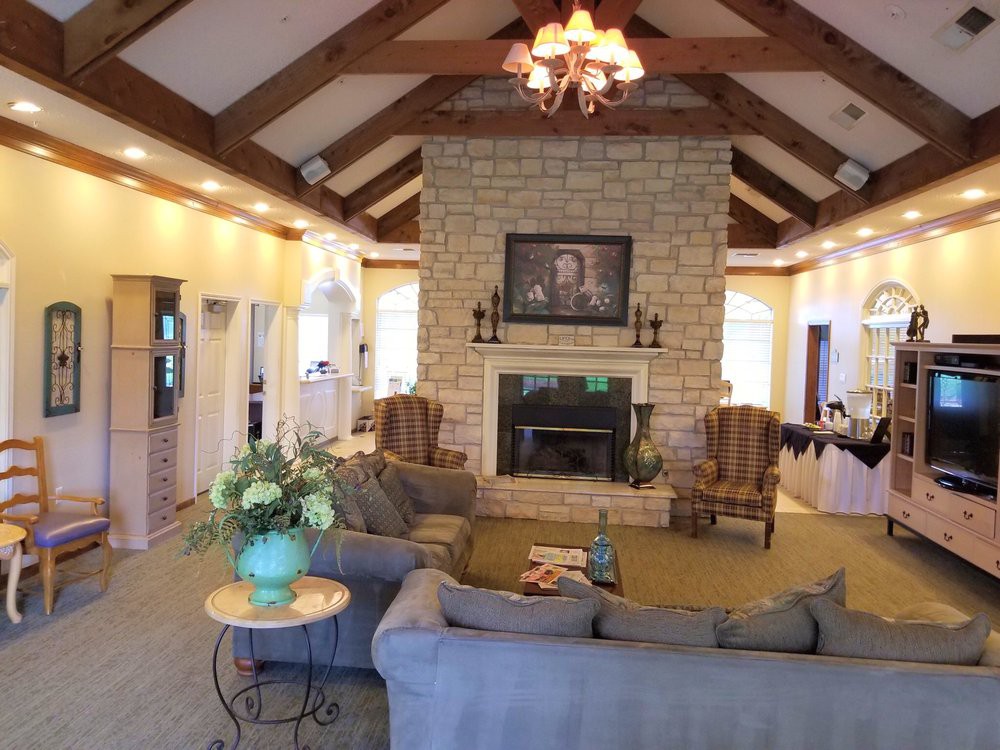 A spacious living room with a stone fireplace, comfortable seating, and exposed ceiling beams.