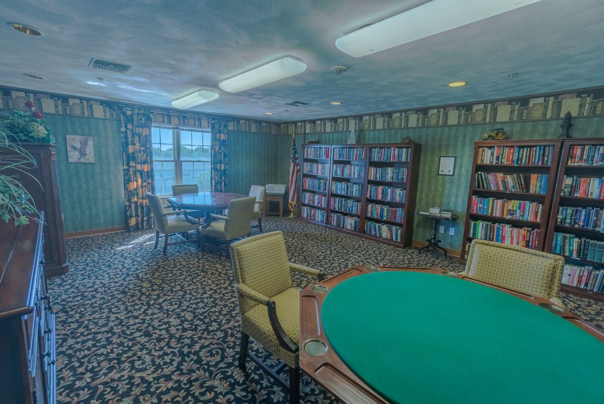 A cozy library room with bookshelves and seating areas for reading and games.