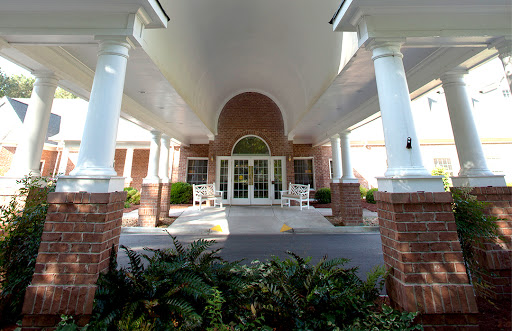 The elegant entrance of a residential building framed by columns and lush greenery.