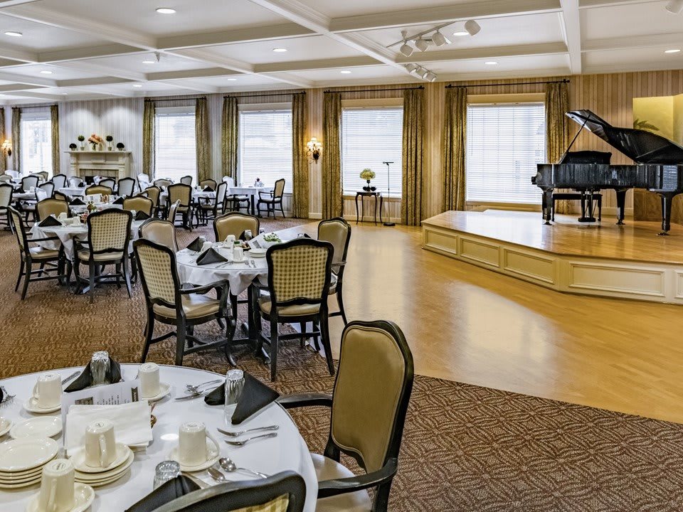A well-appointed dining area with a stage and grand piano, ready for an elegant event.