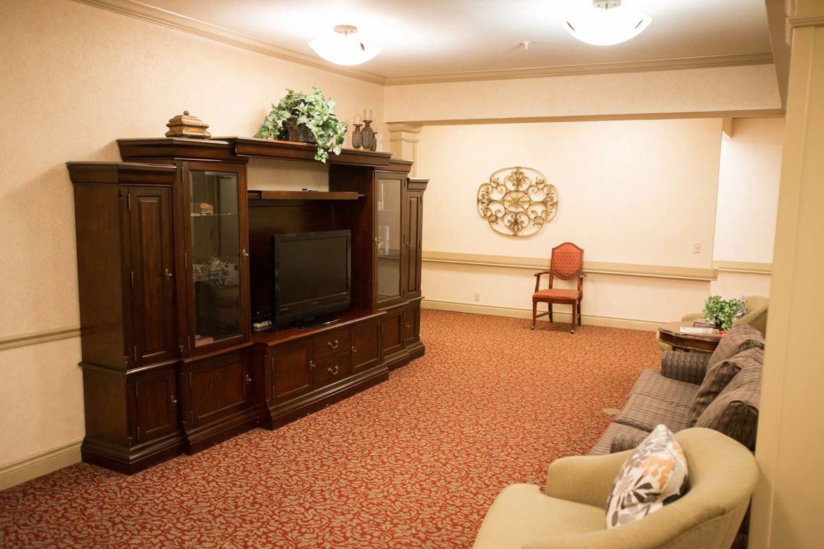 A cozy living room featuring a large wooden cabinet with a TV, comfortable seating, and warm decor.