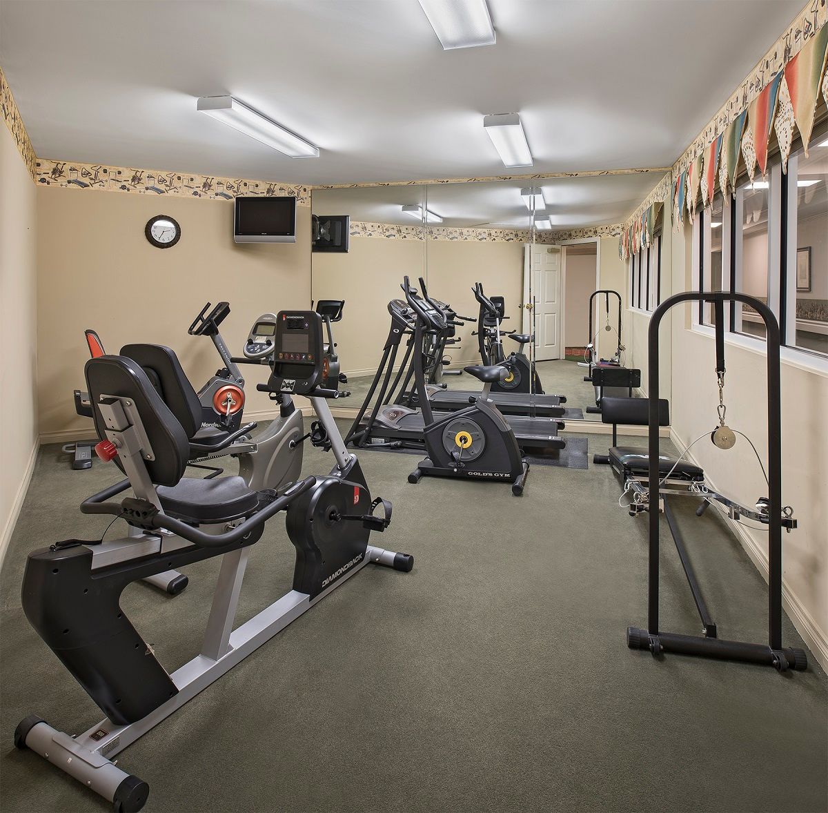 A small gym with various fitness equipment including exercise bikes and treadmills.